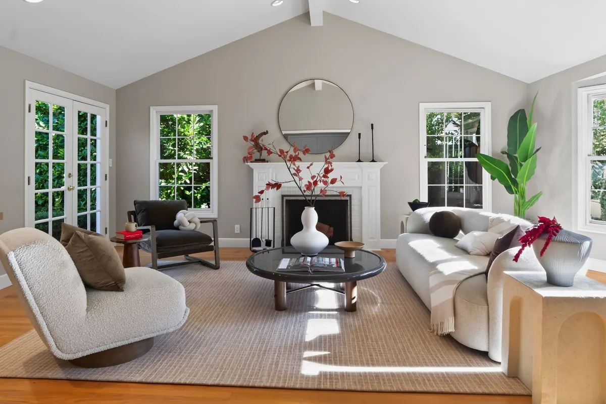 Bright staged living room with vaulted ceiling and fireplace