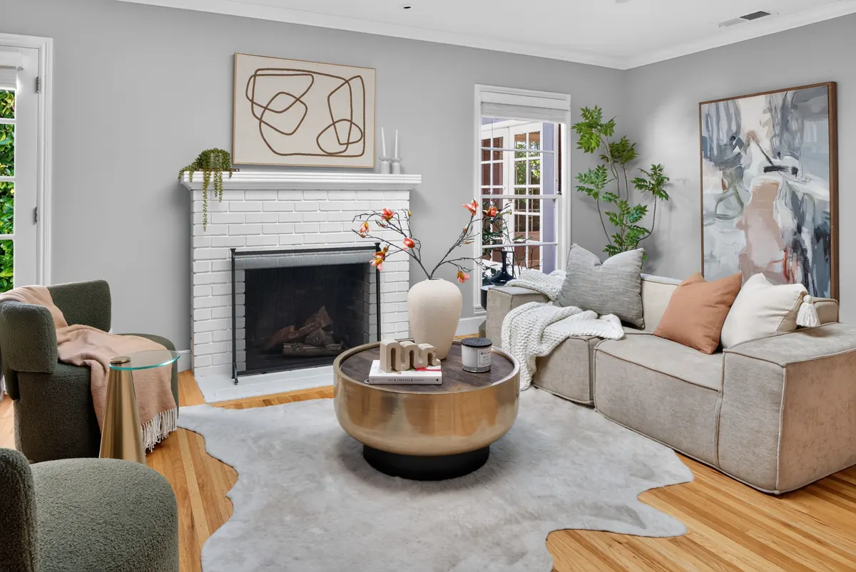 Living room by a white brick fireplace with a brass drum coffee table