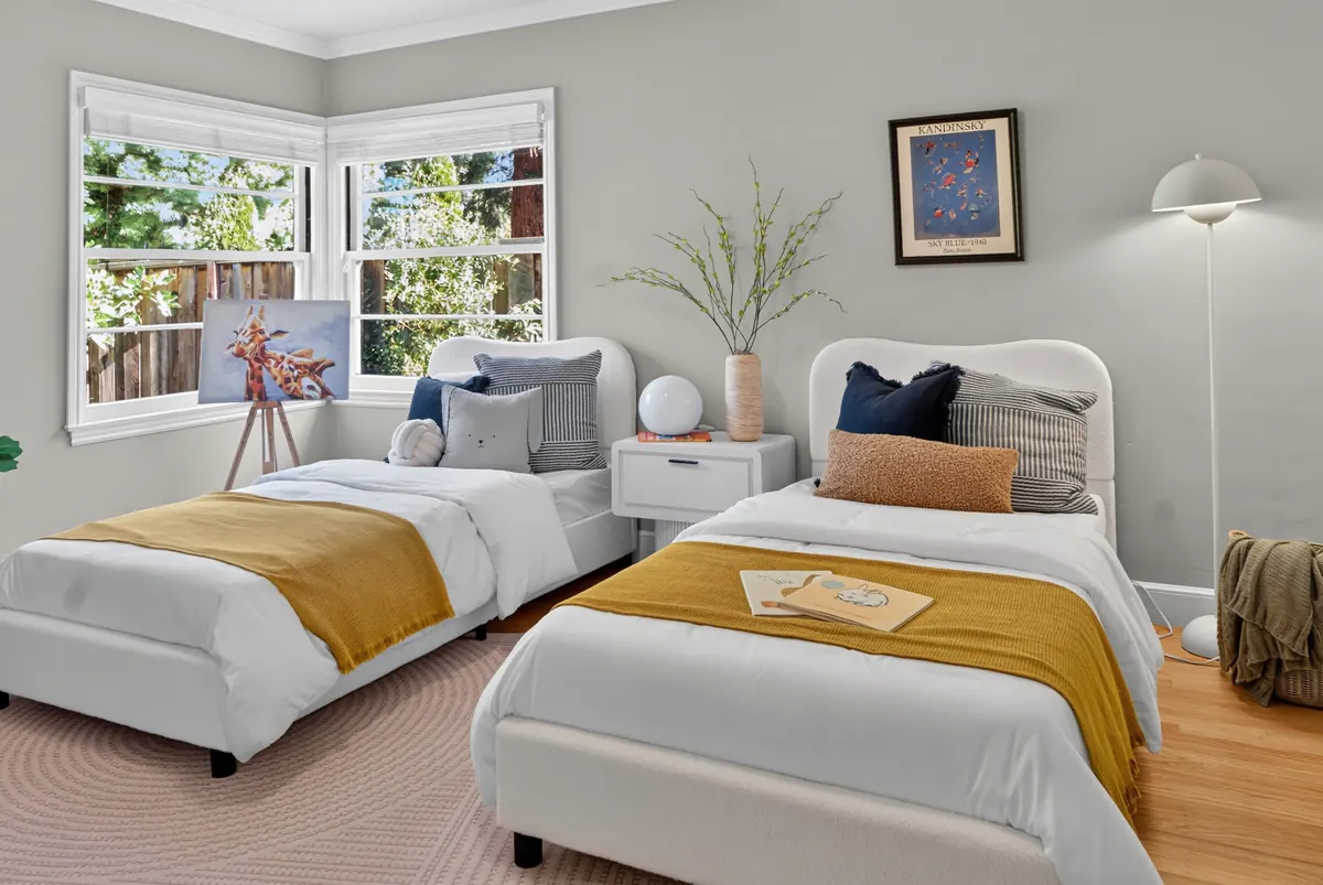 Twin bedroom with mustard throws and a corner window